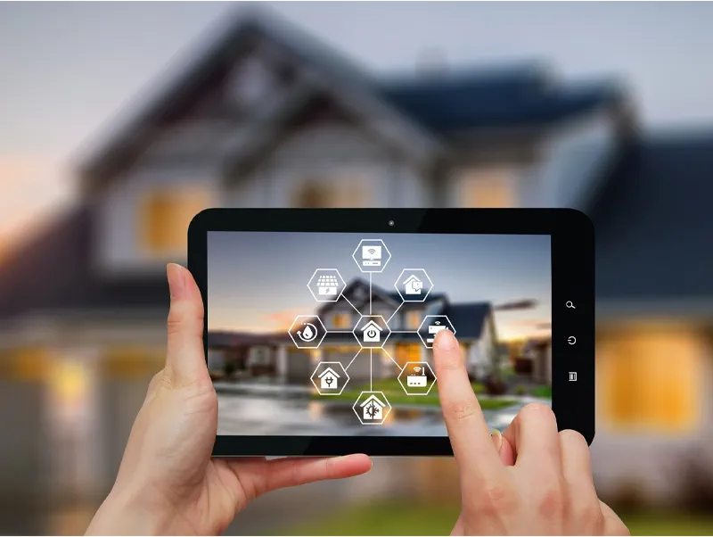 Tablet mit Smart-Home-Steuerung vor einem Haus: Vernetzte Haustechnik aus einer Hand